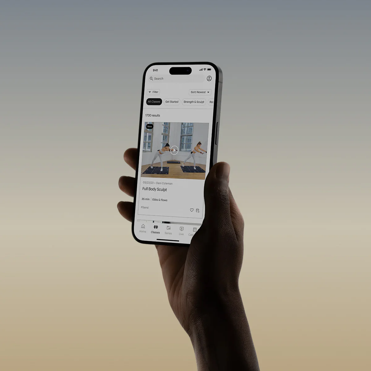 Hand holding a smartphone displaying an image of a PVOLVE studio class